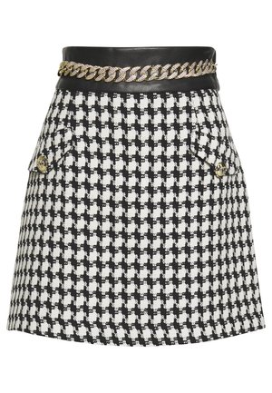 Minigonna pied-de-poule bianca e nera con fascia in pelle nera e dettaglio catena dorata, con due tasche anteriori con patta e bottoni dorati.