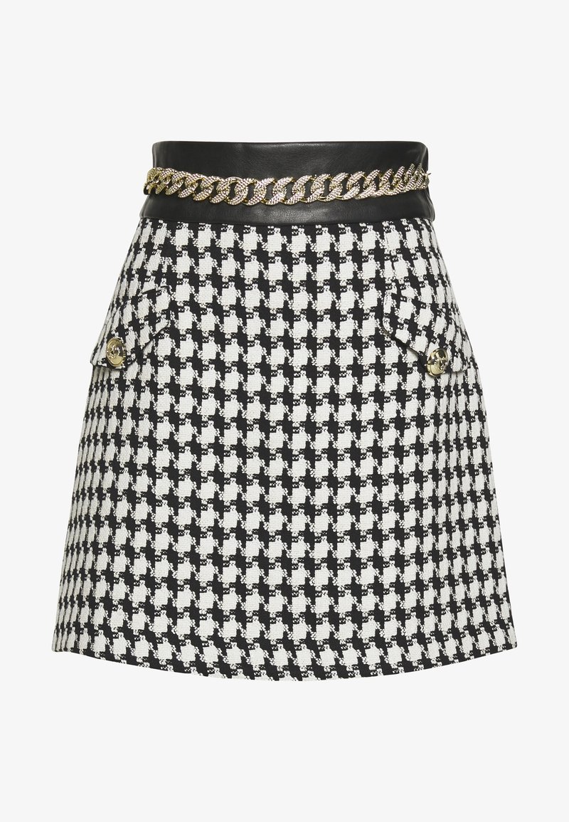 Mini-jupe pied-de-poule noir et blanc avec taille en cuir noir et détail chaîne dorée, avec deux poches avant à rabat avec boutons dorés.