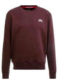 Sudadera burdeos de manga larga, cuello redondo y puños de canalé. Presenta un pequeño logo blanco en el pecho y un forro rojo dentro del cuello.
