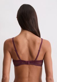 Bralette de encaje burdeos con tirantes delgados ajustables y un cierre de gancho en la parte posterior; detalles de patrón intrincado en la banda.