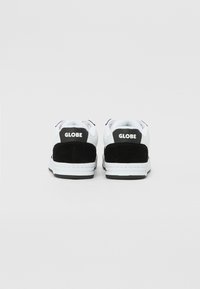 White and black sneakers featuring a suede panel and logo at the heel, with a rubber sole and stitched detailing.