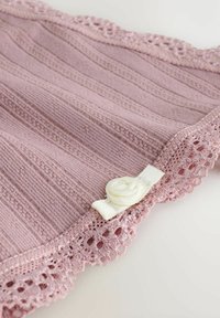 Lyserød strikket stof med vandret ribbe, der har en blonder trim og en hvid knapaccent designet som en rose i kanten.