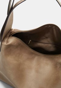 Braune Kunstwildleder-Handtasche mit weit öffnendem Hauptfach, Innenreißverschlussfach und glatter Textur. Weiches, minimalistisches Design mit einem einzigen Schulterriemen.