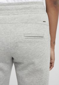 Grå bomullssweatpants med elastisk midja, en liten tryckt logotyp och en enda bakficka med subtila sömdetaljer.
