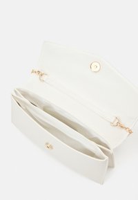 Vit syntetisk clutch med guldknappstängning, som har två inre fack och en kedjehandtag. Slät textur.