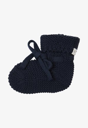 Chausson en tricot bleu marine avec une texture douce, des détails à nouer et un revers plié. Forme arrondie avec une semelle plate pour les nourrissons.