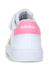 Vit lädersneaker med en rosa accent vid hälen, har en logotyp, mjuk inredning och en strukturerad sula för grepp och stöd.