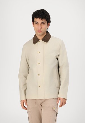 Giacca beige con colletto in velluto a coste marrone, chiusura a bottoni a pressione e tasche laterali. Texture liscia con un design a tinta unita.