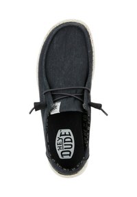 Zapato de tela gris oscuro con punta redondeada, que presenta una suela blanca moteada y cordones elásticos. El interior tiene un diseño de patrón. Logo visible.