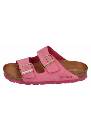 Sandale en suède rose avec deux sangles à boucle, semelle en liège et semelle extérieure en caoutchouc texturé. Elle présente une forme arrondie et un talon plat.