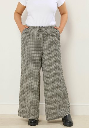 Löysät lahkeet musta-valkoisessa ruutukuosissa, joustava vyötärönyöri ja sivutaskut. Valmistettu kevyestä kankaasta.