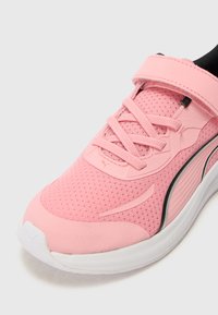 Chaussure de sport rose avec une tige en mesh respirant, des lacets plats et une semelle blanche rembourrée. Elle dispose d'une sangle à fermeture velcro pour un ajustement sécurisé.