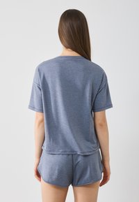 Kurzärmliges T-Shirt aus blauen Melange-Baumwolle und passende Shorts. Das T-Shirt hat einen runden Ausschnitt; die Shorts haben einen elastischen Taillenbund.