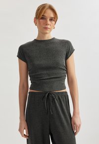 Top corto de tejido acanalado gris oscuro con mangas cortas. Presenta un diseño ajustado y textura fruncida, combinado con pantalones de cintura elástica a juego.