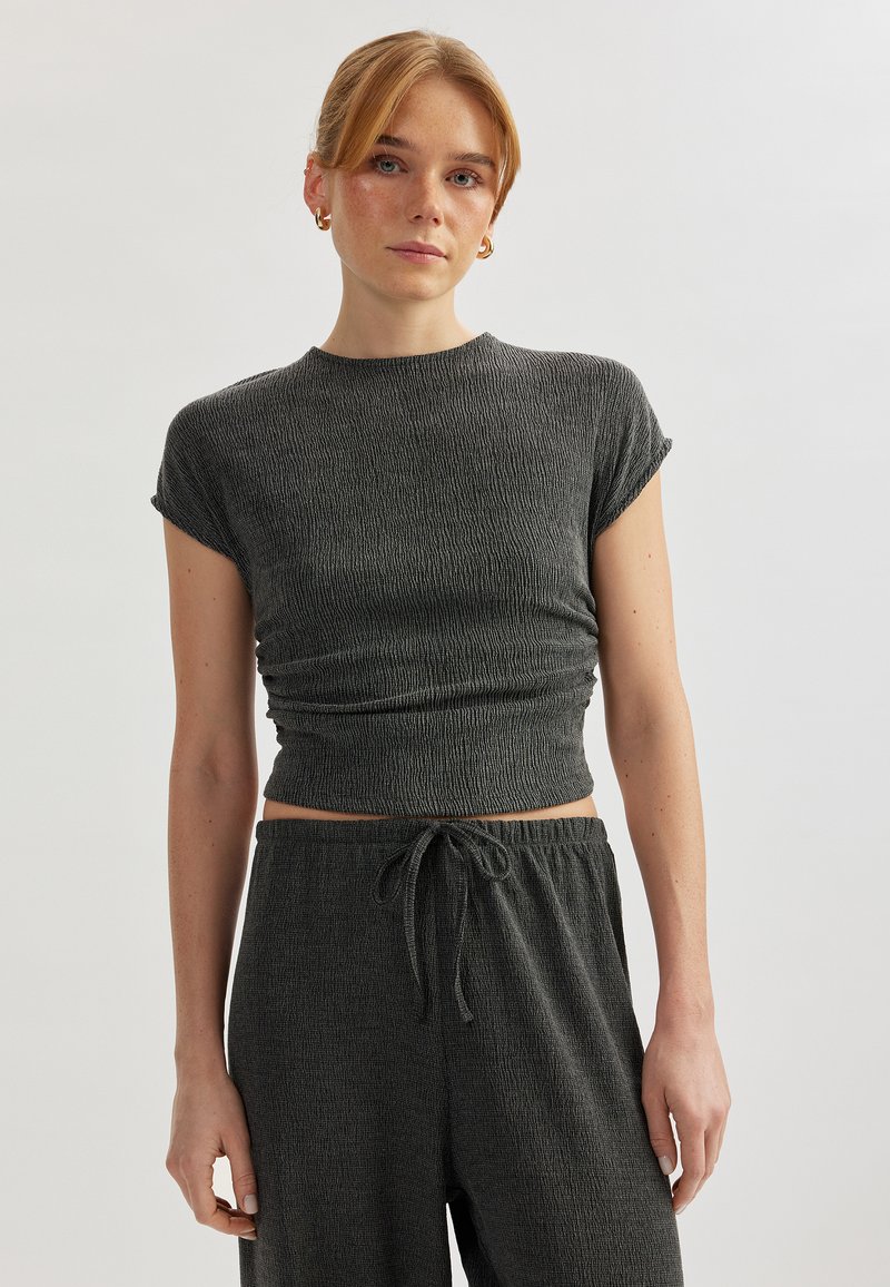Top corto de tejido acanalado gris oscuro con mangas cortas. Presenta un diseño ajustado y textura fruncida, combinado con pantalones de cintura elástica a juego.