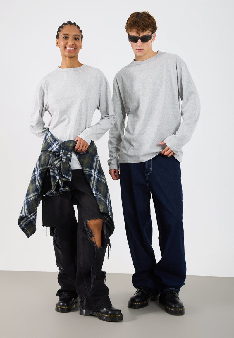 Cămăși gri cu mâneci lungi, pantaloni negri uzați cu margini destrămate, flanel în carouri legat la brâu și încălțăminte neagră. Accesorii minime.