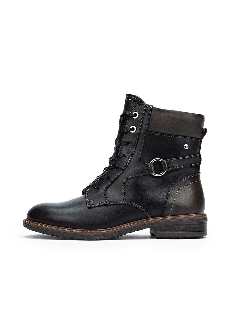 Bottine en cuir noir avec lacets à l'avant, bout rond et accents marron. Dotée d'une boucle sur le côté et d'une finition texturée. Talon bas empilé.
