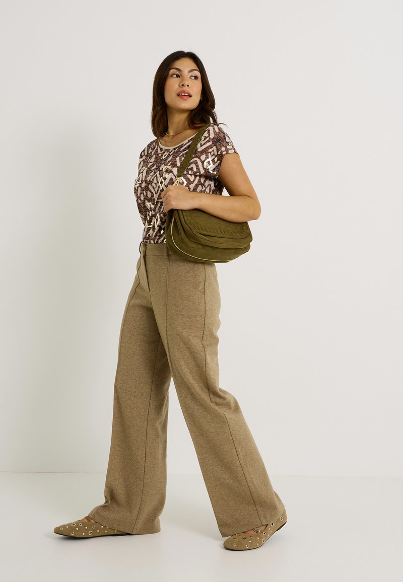 Top corto de manga corta con estampado marrón, pantalones de pierna ancha beiges, bolso de hombro verde oliva y zapatos planos marrón claro con acentos circulares.