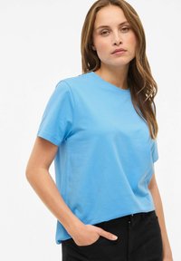 Jasnoniebieska bawełniana koszulka z krótkimi rękawami, okrągłym dekoltem i luźnym krojem. Gładka faktura, bez wzorów i widocznych logo.