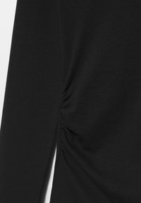 Sort langærmet top med smockdetalje i siden, lavet af blødt bomuldsstof, med klassisk pasform og glat tekstur.