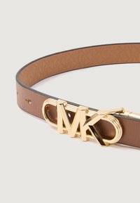 Cinturón de cuero marrón con un acabado texturizado, que presenta una hebilla metálica dorada con las iniciales "MK". Ajustable con múltiples agujeros.