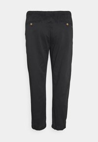 Zwarte broek met een relaxte pasvorm, elastische tailleband en ritszakken aan de achterkant. Heeft een omslagonderkant met een lichte gather bij de enkels.