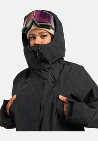 Schwarze, isolierte Jacke mit hohem Kragen und verstellbarer Kapuze. Verfügt über große Vorder Taschen, elastische Bündchen und eine glatte Textur.