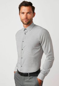 Grau gemustertes Button-up-Hemd mit klassischem Kragen, langen Ärmeln und schwarzen Knöpfen, kombiniert mit grauen Hosen und einem schwarzen Gürtel.
