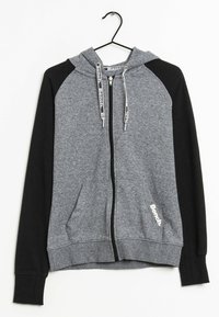 Sweat à capuche zippé gris et noir avec une capuche, des poches avant, des manches contrastées et un logo blanc "Bench" sur le côté inférieur droit.