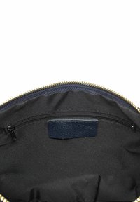 Navy interieur van een zippered tas met een gouden rits. Beschikt over een klein zippered vakje en een texturelabel van leer met de merknaam.