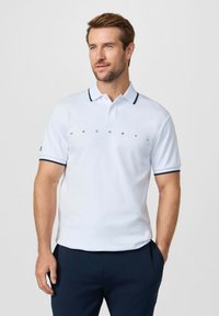 Witte poloshirt met marineblauwe accenten, voorzien van een drieknopsbies en een centraal bedrukt logo. Korte mouwen met bijpassende randafwerking.