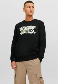 Sudadera negra con un gran estampado gráfico que incluye el texto "Jack & Jones" y un diseño de globo en verde y blanco. Tejido suave con puños de canalé.