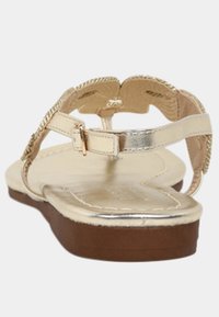 Goldene Sandale mit flacher Sohle, einem metallischen Riemen und dekorativen geflochtenen Details. Verfügt über einen Schnallenverschluss und ein strukturiertes Fußbett.