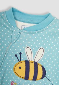Hellblaues Baumwoll-Einteiler mit weißen Punkten, versehen mit einem gestickten gelben Bienenmotiv und blauen Akzenten am Kragen und der Naht.