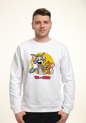 Hvid sweatshirt med grafik af tegnefilmsfigurerne Tom og Jerry mod en gul cirkelformet baggrund. Fremstillet i bomuldsmateriale, med ribkanter.