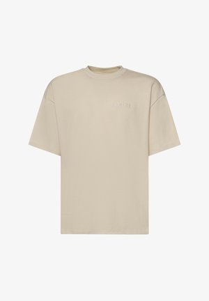 T-shirt beige a maniche corte con scollo rotondo e logo "AMIRI" ricamato discretamente sulla parte superiore sinistra del petto.