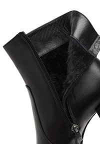 Bottine en cuir noir avec un intérieur en fourrure noire douce, dotée d'une fermeture éclair sur le côté et d'une finition lisse.