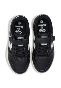 Schwarze Sportschuhe mit weißen Akzenten, die Schnürsenkel und einen Klettverschluss haben, von oben betrachtet. Die Innensohle zeigt das "Hummel"-Label.