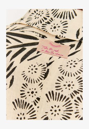 Light beige fabric with black floral pattern. Features a label with pink text saying, "Take the risk or lose the chance."