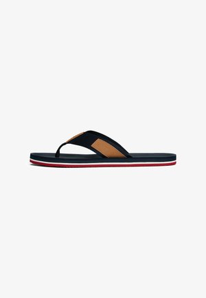 Schwarz-braune Flip-Flops mit einem strukturierten Riemen, einer Schaumfußbett und einer gestreiften rot-weiß-blauen Sohle. Flaches Design für einfaches Tragen.