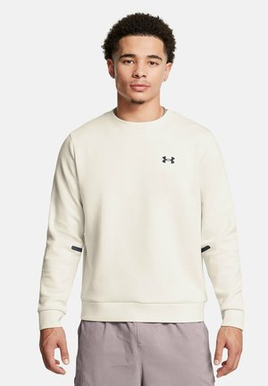 Jasno beżowy sweatshirt wykonany z mieszanki bawełny, z okrągłym dekoltem, długimi rękawami, małym czarnym logo na klatce piersiowej oraz bocznymi akcentami.