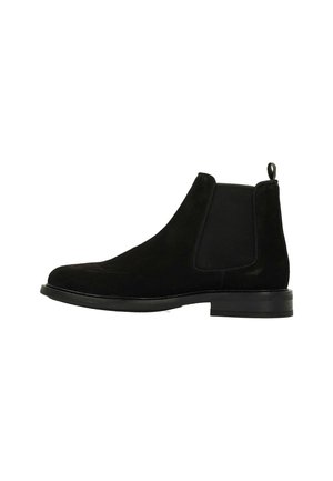 Black suede Chelsea boots with elastic side panels, rounded toe, and a pull tab on the heel. Flat rubber sole, minimalist design.