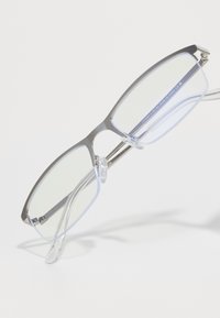 Óculos de metal com lentes transparentes, apresentando um design elegante, forma angular e hastes transparentes. Detalhes em prateado na armação.