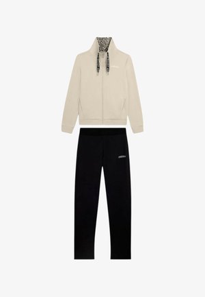 Giacca beige con zip con colletto interno a stampa leopardata e coulisse nere abbinata a pantaloni neri, entrambi con il logo Freddy.