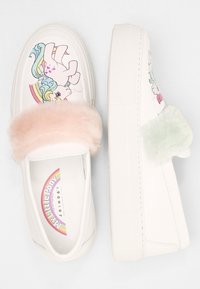 Białe trampki na platformie z wzorem kreskówkowego jednorożca, z różowym paskiem z sztucznego futra oraz miętowozielonym pomponem po boku.