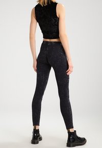 Černé, elastické legíny s texturovaným, vybledlým povrchem. Spárované s cropped sametovým topem a černými lakovanými kotníkovými botami.
