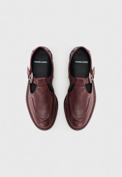 Μπορντό δερμάτινα παπούτσια με κλειστή μύτη, κομμένες πλευρές και λουράκι με αγκράφα. Το σχέδιο περιλαμβάνει ραφές και υφή φινιρίσματος.