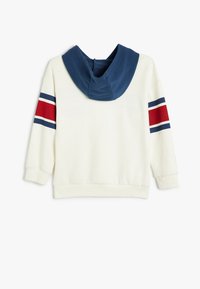 Sudadera blanca con capucha azul marino, con acentos de rayas rojas y azules en las mangas. Tela suave, corte relajado y puños acanalados.