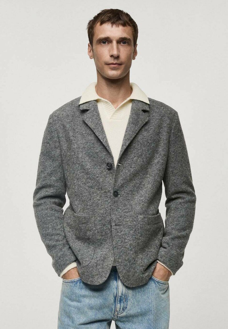 Gray wool blend jacket with a tailored fit, notched lapels, two front pockets, and a single button closure over a white collared shirt.