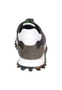 Sportschuh mit braunem Wildleder und schwarzem Lederoberteil, weißer Ferse, grünen Schnürsenkeln und einer strukturierten, mehrfarbigen Gummisohle mit Stollen.